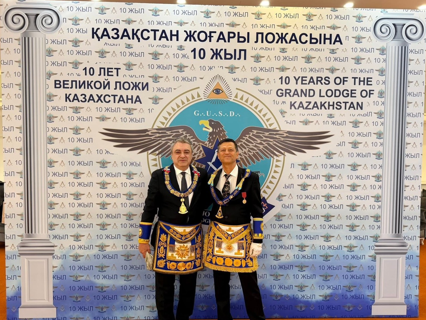 Два масона в регалиях у баннера десятилетия Великой Ложи Казахстана